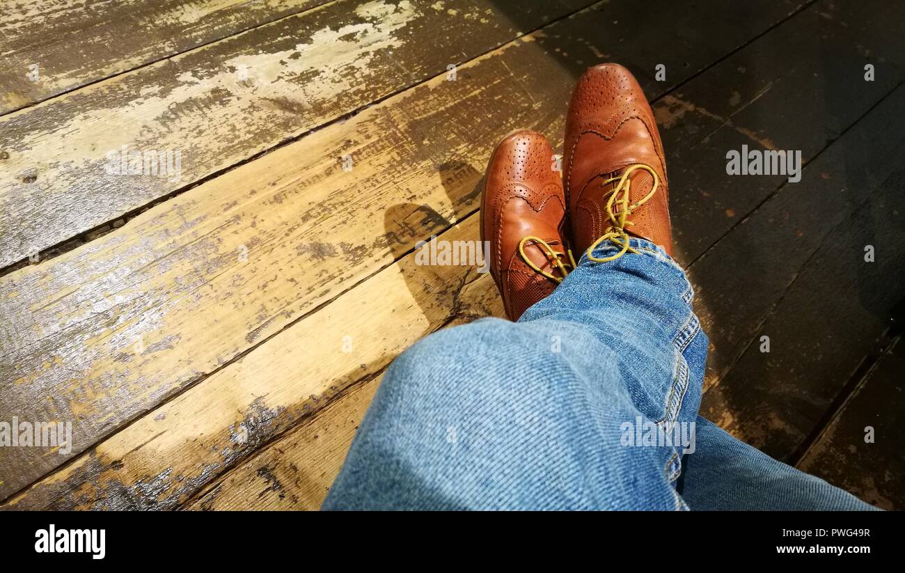 Brown scarpe di cuoio, jeans, isolata su uno sfondo di legno Foto Stock