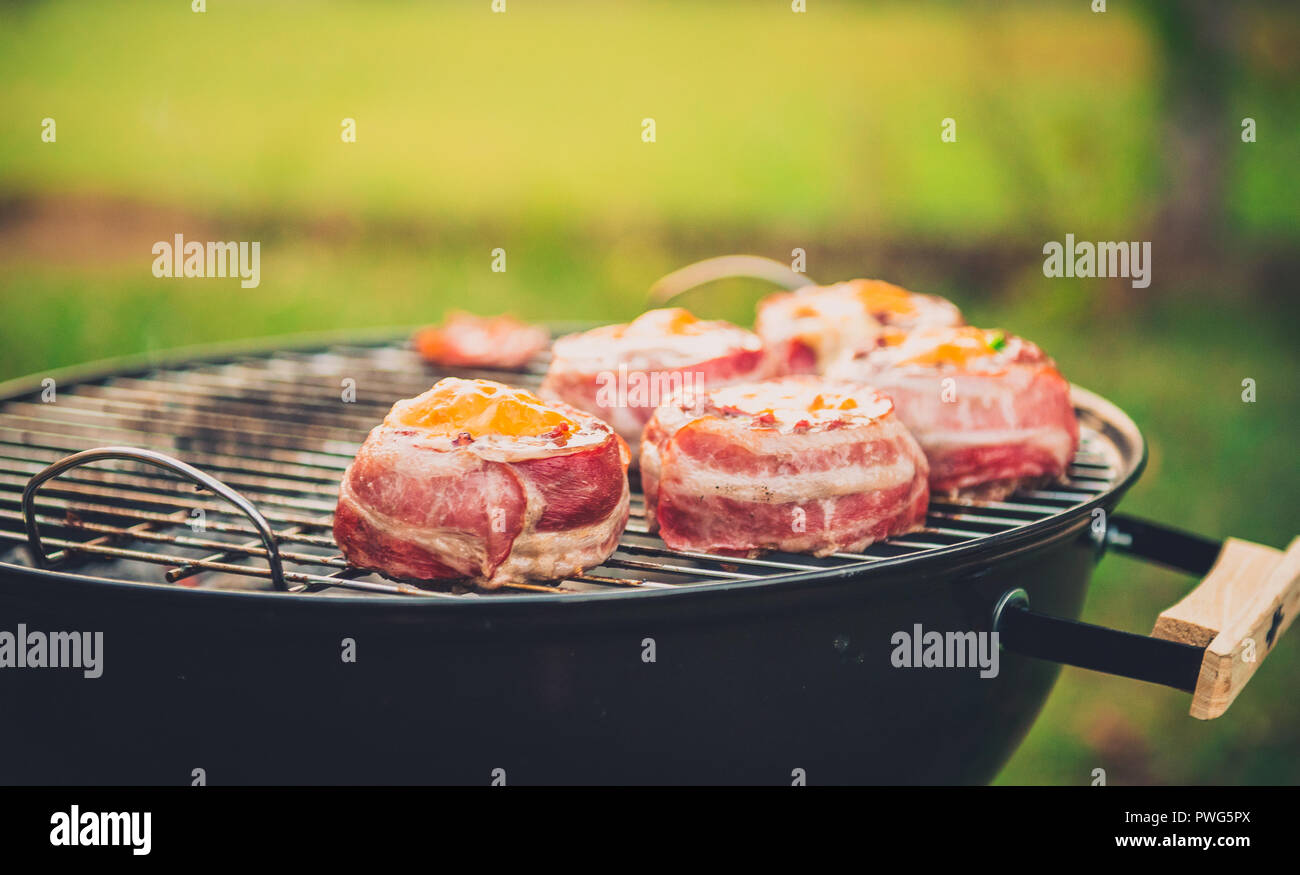 Rendendo fatta in casa birra può Bacon gli hamburger sul grill barbecue. La preparazione di polpette ripiene, avvolto in pancetta e grigliare sul calore indiretta nella natura a bac Foto Stock