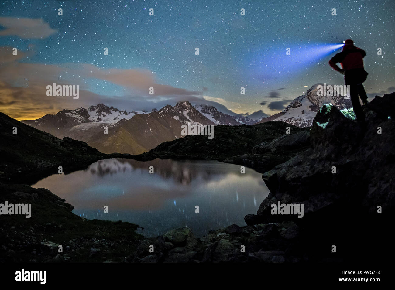 Escursionista sulla parte superiore delle rocce ammirando le stelle si riflette in Lacs de Cheserys con il massiccio del Monte Bianco sullo sfondo, Chamonix Haute Savoie, Francia Foto Stock
