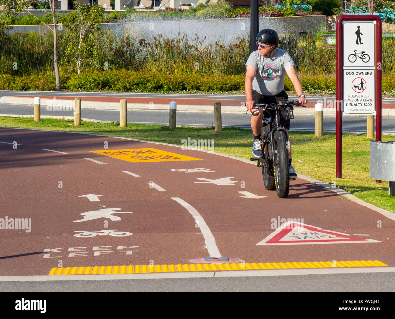 Ciclista grasso di equitazione Bicicletta bici Escursioni in bicicletta su un percorso cycleway nel Burswood Perth Western Australia Foto Stock