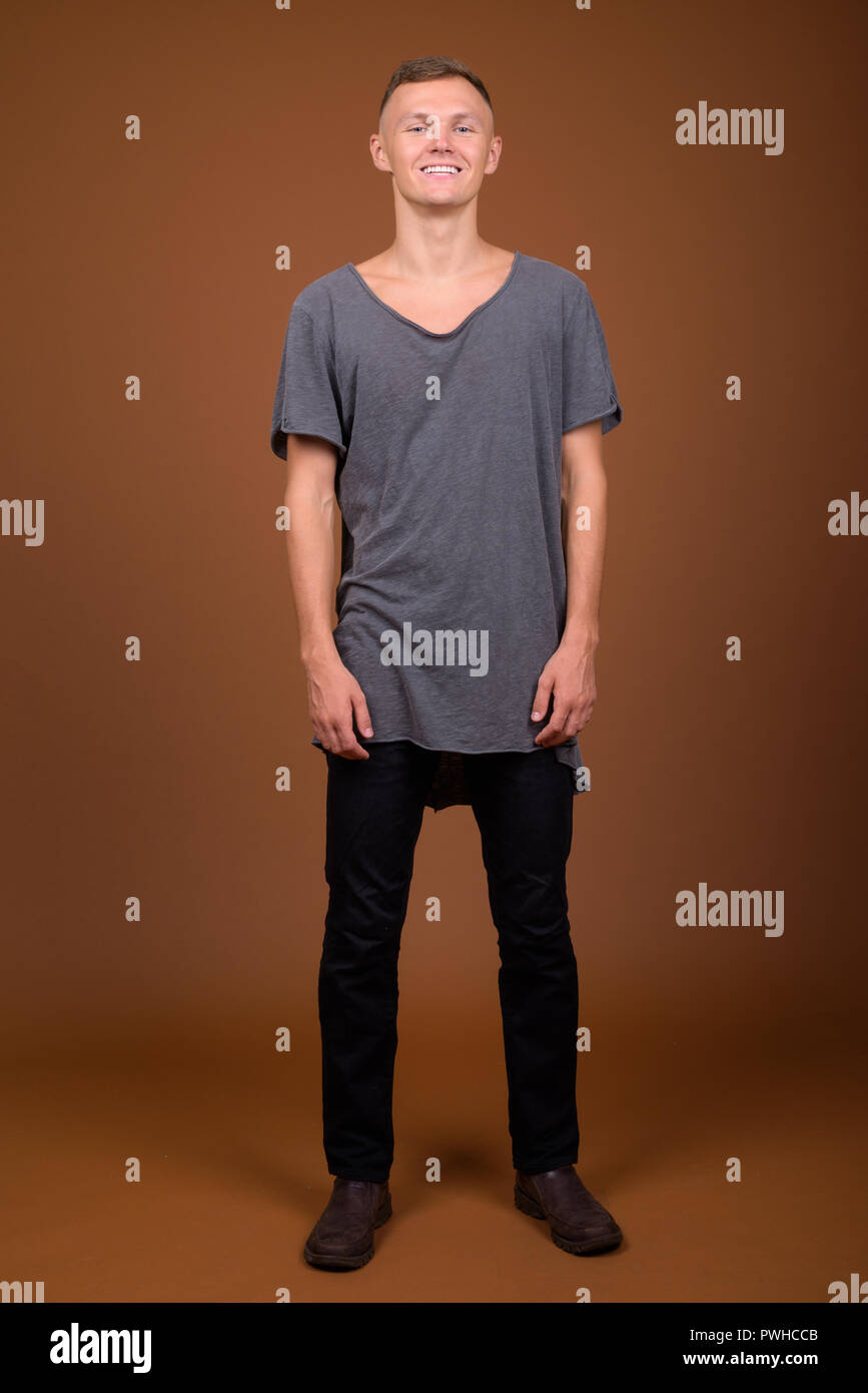 Giovane uomo che indossa maglietta grigio contro sfondo marrone Foto Stock