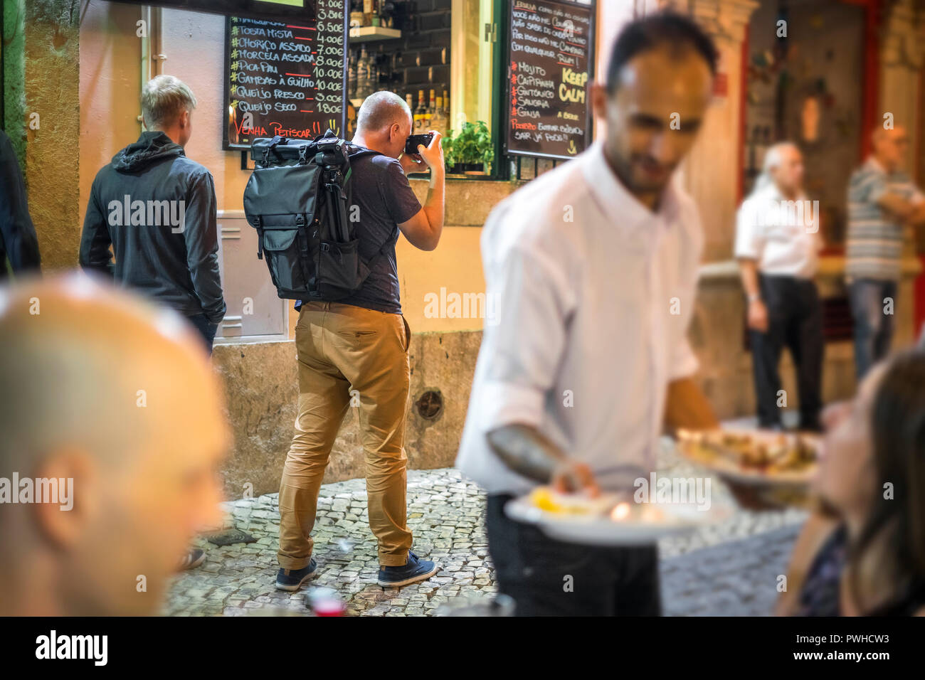 Fotografo di scattare le foto di vivaci strade con ristoranti di Alfama, Lisbona, Portogallo Foto Stock