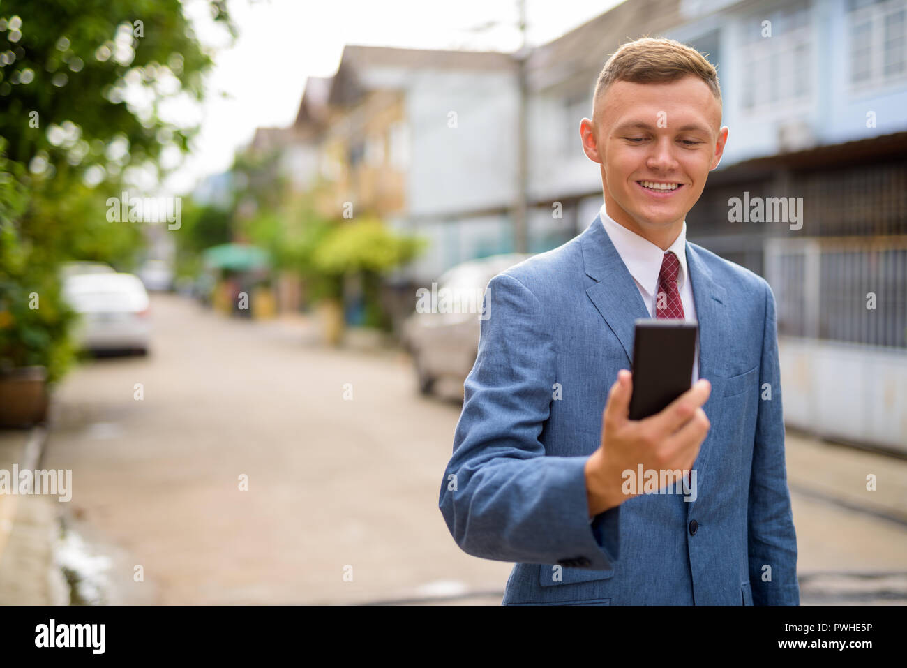 Giovane imprenditore utilizzando il telefono cellulare nelle strade all'aperto Foto Stock