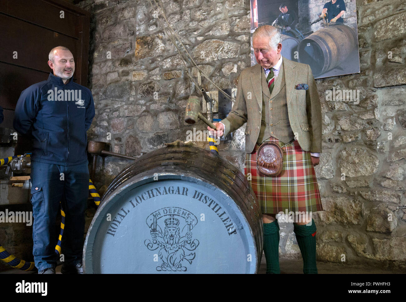 Il Principe di Galles, noto come il Duca di Rothesay mentre in Scozia, riempie un nuovo whisky botte, al fianco di operatore senior Ryan Cromar, durante una visita al Royal Lochnagar Distillery a Crathie sulla Royal Deeside. Foto Stock