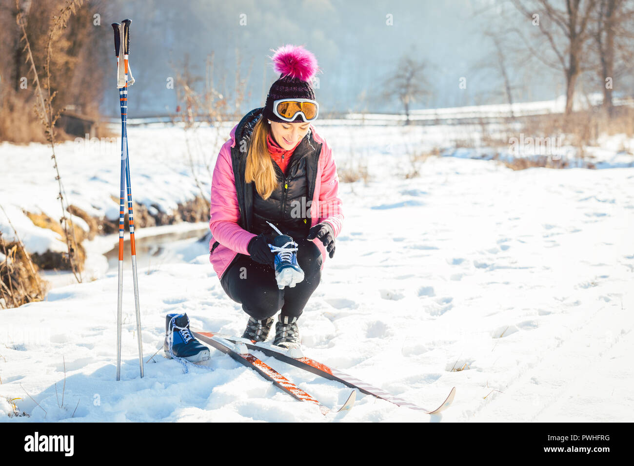 Donna cross country sciatore mettendo su sci Foto Stock