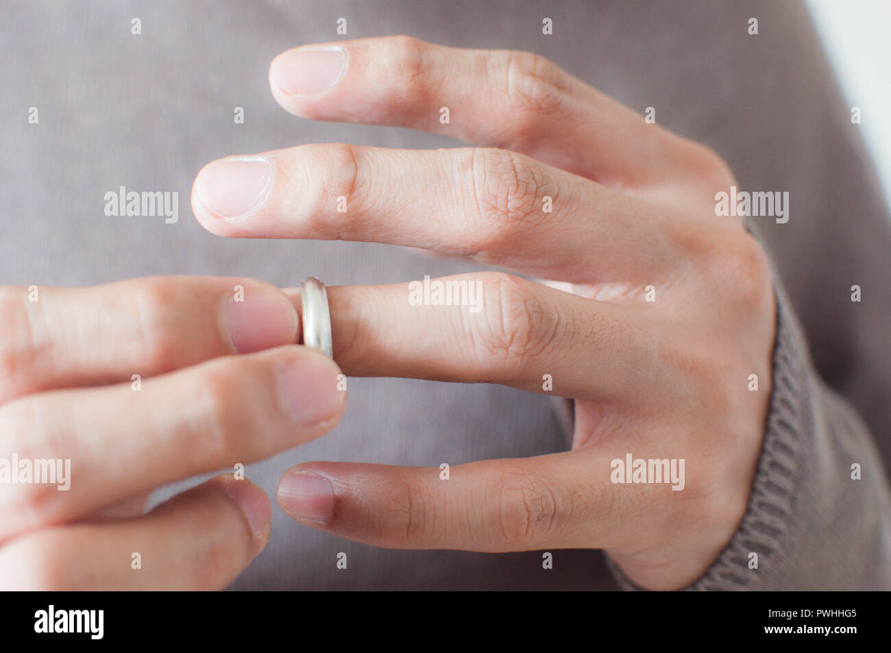 Chiudere fino alle mani di un uomo che indossa un anello d'argento su anello dito Foto Stock