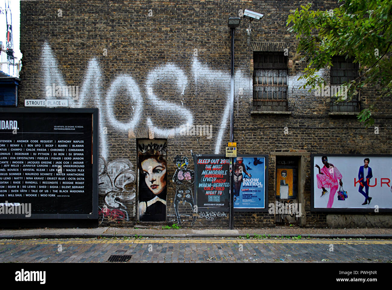 GRAFFITI, Arte di strada,BILL adesivi & annunci sullo stesso VICTORIAN East London Wall. Foto Stock
