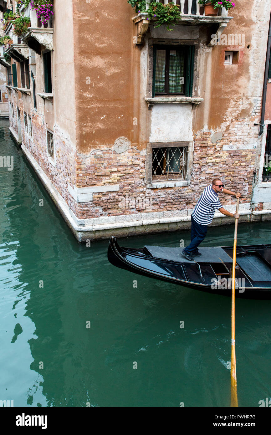 Una gondola navigando attraverso i Backstreet canali di Venezia, Italia Foto Stock