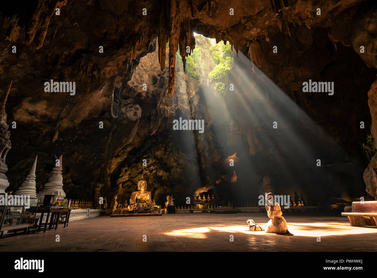 La donna il culto della statua di Buddha con luce solare nella grotta di Khaoluang,Phetchaburi Provincia, Thailandia. Questo posto è un luogo pubblico. Le persone hanno acce Foto Stock