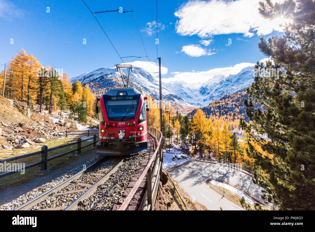Bernina Express circondato da boschi colorati e cime innevate del Bernina Cantone dei Grigioni Engadina Svizzera Europa Foto Stock