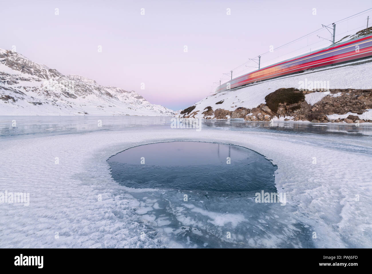 Il Bernina Express treno passa accanto al lago congelato Bianco del Bernina cantone dei Grigioni Engadina Svizzera Europa Foto Stock