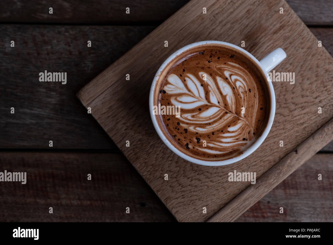 Bella forma di latte art caffè servite sul piatto di legno Foto Stock