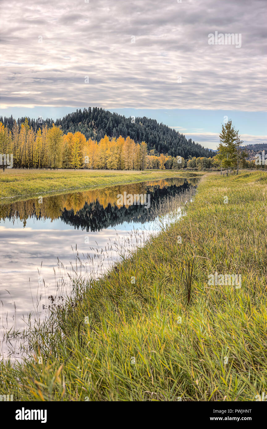 Acqua calma del canale riflette le nuvole nel cielo in una giornata autunnale vicino Bonners Ferry, Idaho. Foto Stock