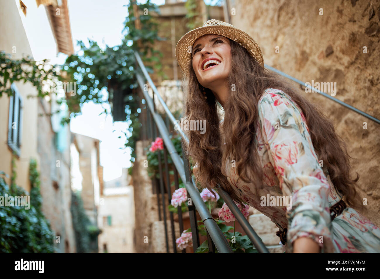 Felice viaggiatore moderno donna in abiti lunghi e cappello di paglia a Pienza, Italia avente tempo di divertimento Foto Stock