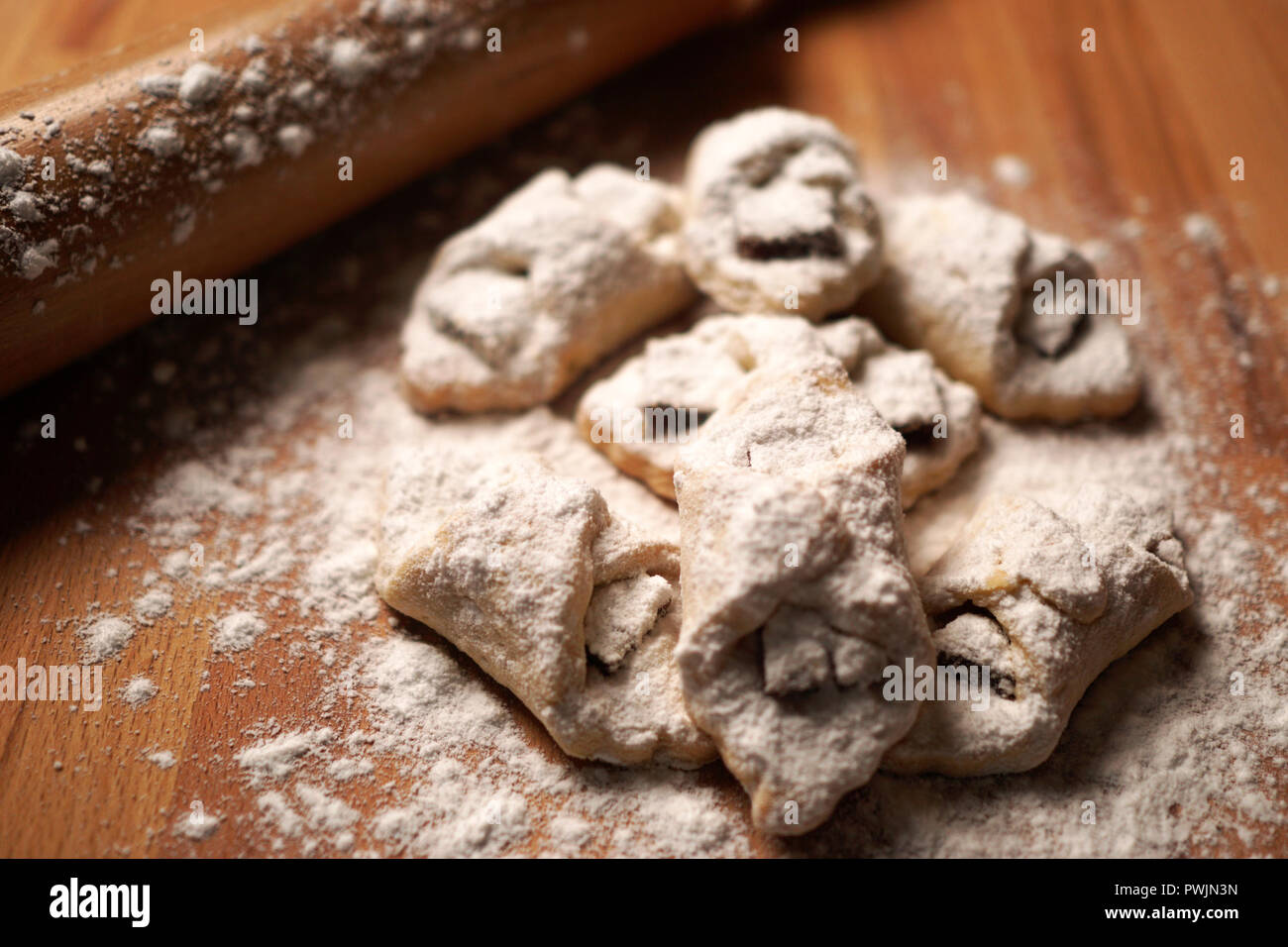 Deliziosi biscotti fatti in casa con mela e cannella decorata con zucchero a velo sulla parte superiore del tavolo di legno. Rullo di pasta in background. Foto Stock