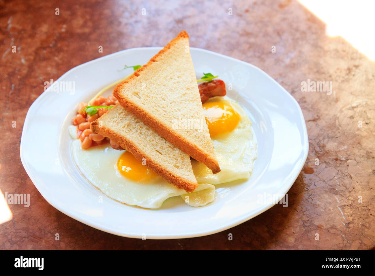 Uova strapazzate con fagioli e toast su una piastra bianca Foto Stock