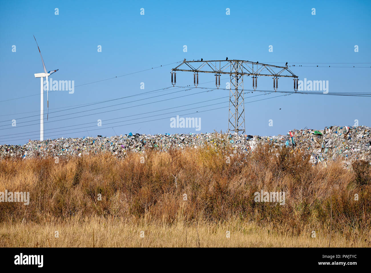 Discarica con un mulino a vento in background, concetto ambientale. Foto Stock