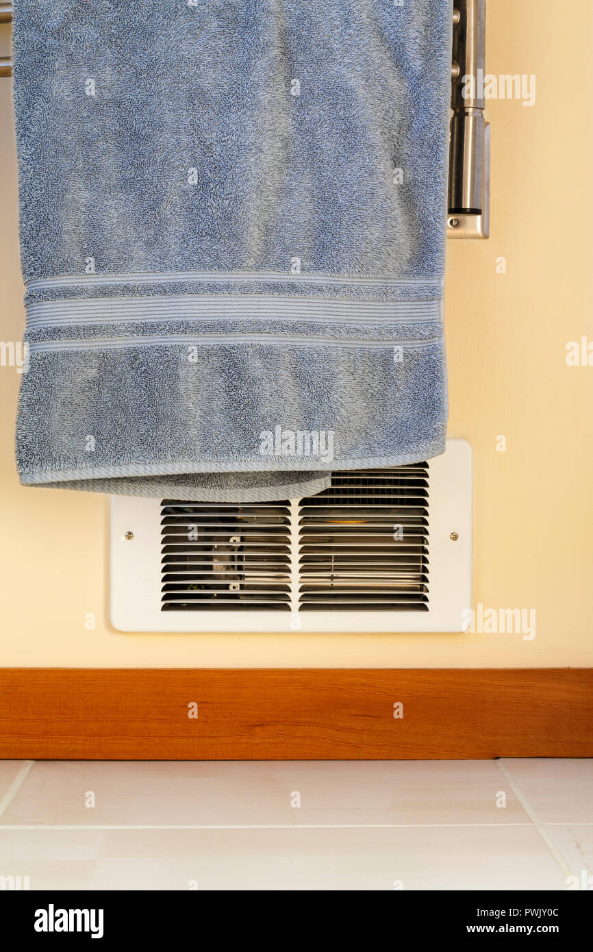 Asciugamano appeso di fronte a parete baseboard elettrico riscaldatore. Casa pericolose home i rischi di incendio. Foto Stock