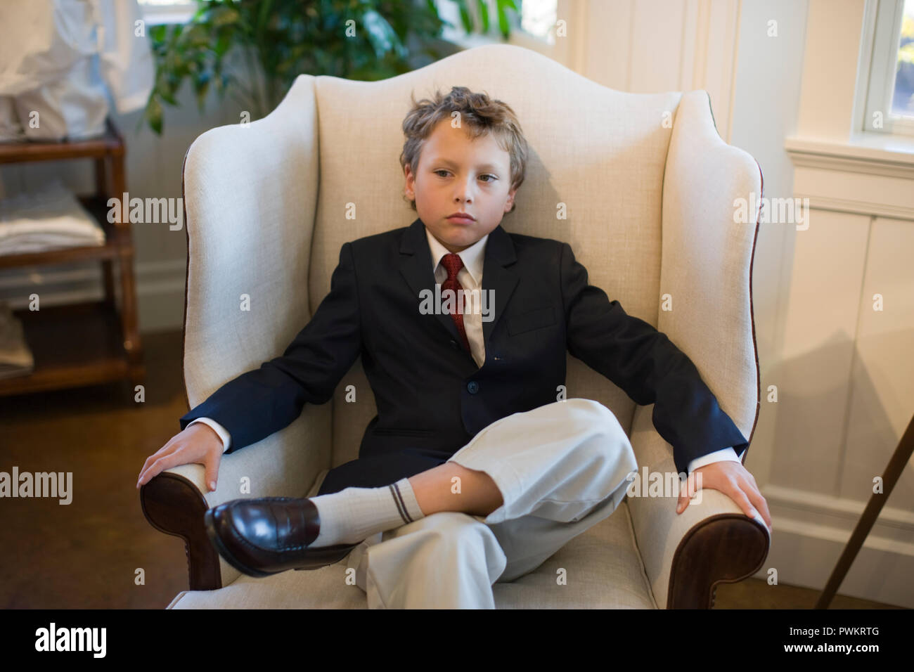 Ragazzo che indossa tuta seduto in poltrona Foto Stock