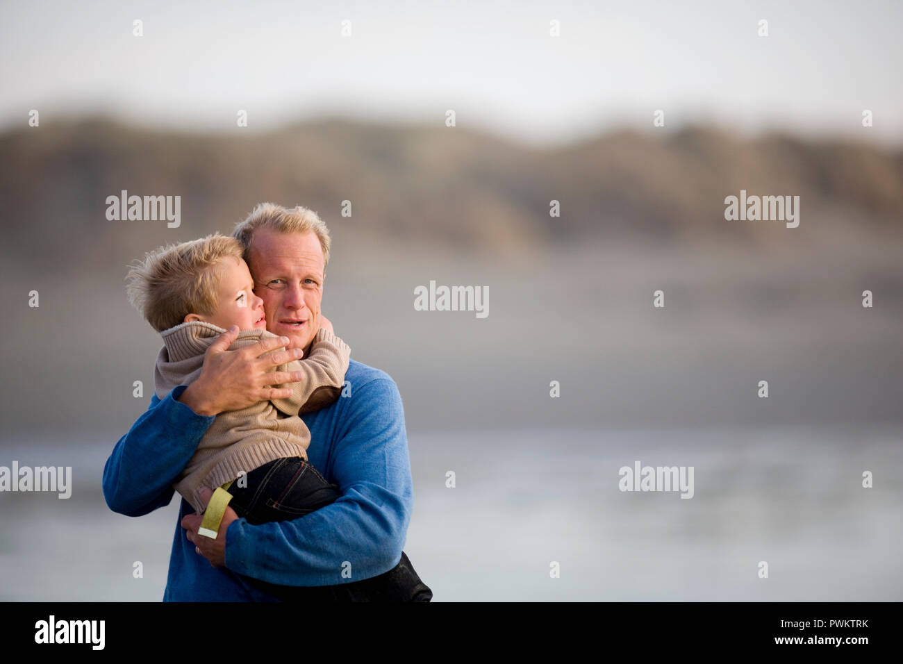 Ritratto di un uomo maturo abbraccia il suo giovane nipote su una spiaggia remota Foto Stock