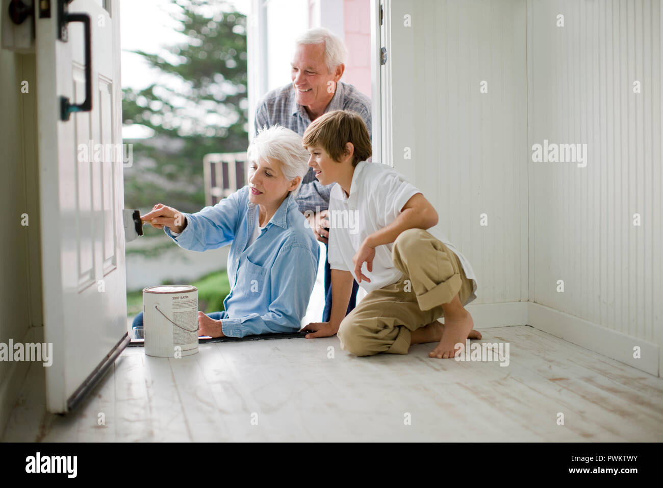 Coppia senior loro verniciatura porta anteriore con il loro nipote. Foto Stock