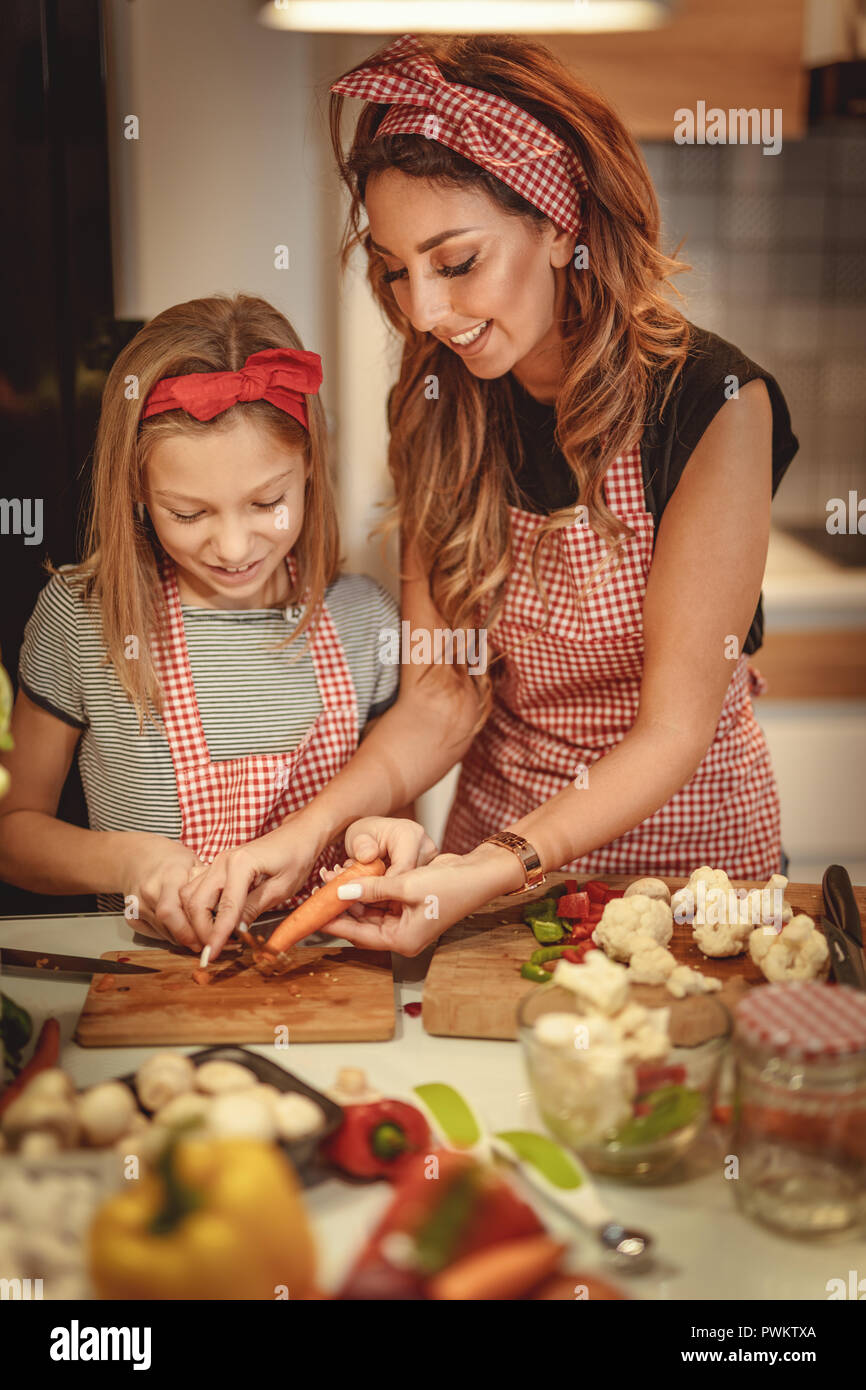 Ritratto di felice madre e figlia cucina insieme in cucina mentre il taglio di vegetali. Foto Stock