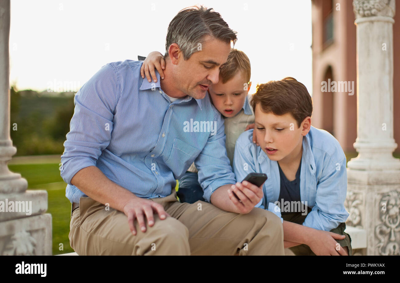 Uomo maturo che mostra il suo cellulare per il suo curioso figli. Foto Stock