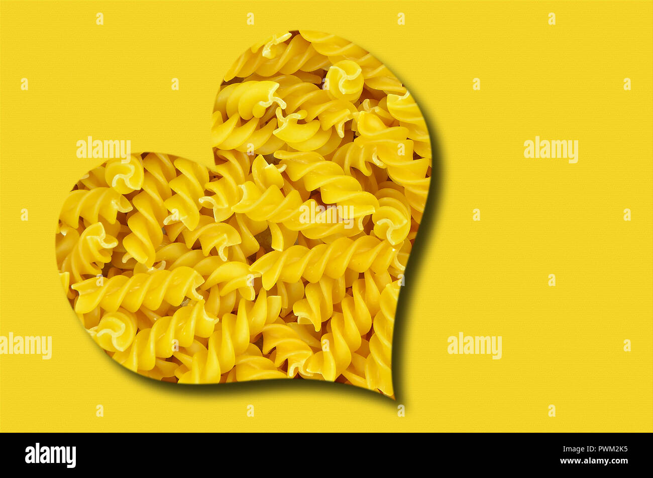 Cuore con pasta su sfondo giallo, vicino, frame completo Foto Stock