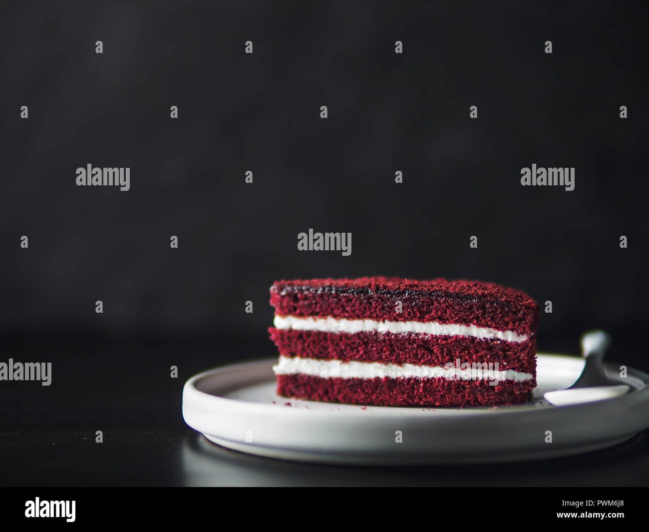 Pezzo di torta rossa del velluto con consistenza perfetta nella piastra opaco nero sul piano portapaziente. Fetta di deliziosa casa torta rossa del velluto con lampone e cioccolato. Copia spazio per il testo. Foto Stock