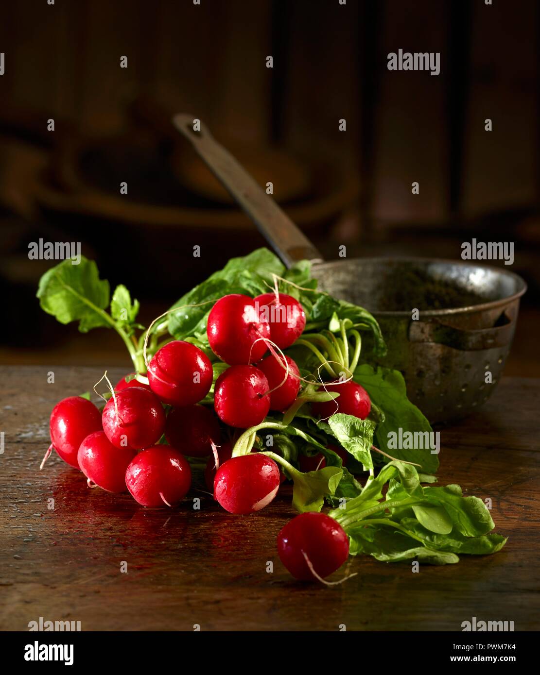Ravanelli davanti a un vecchio setaccio da cucina Foto Stock