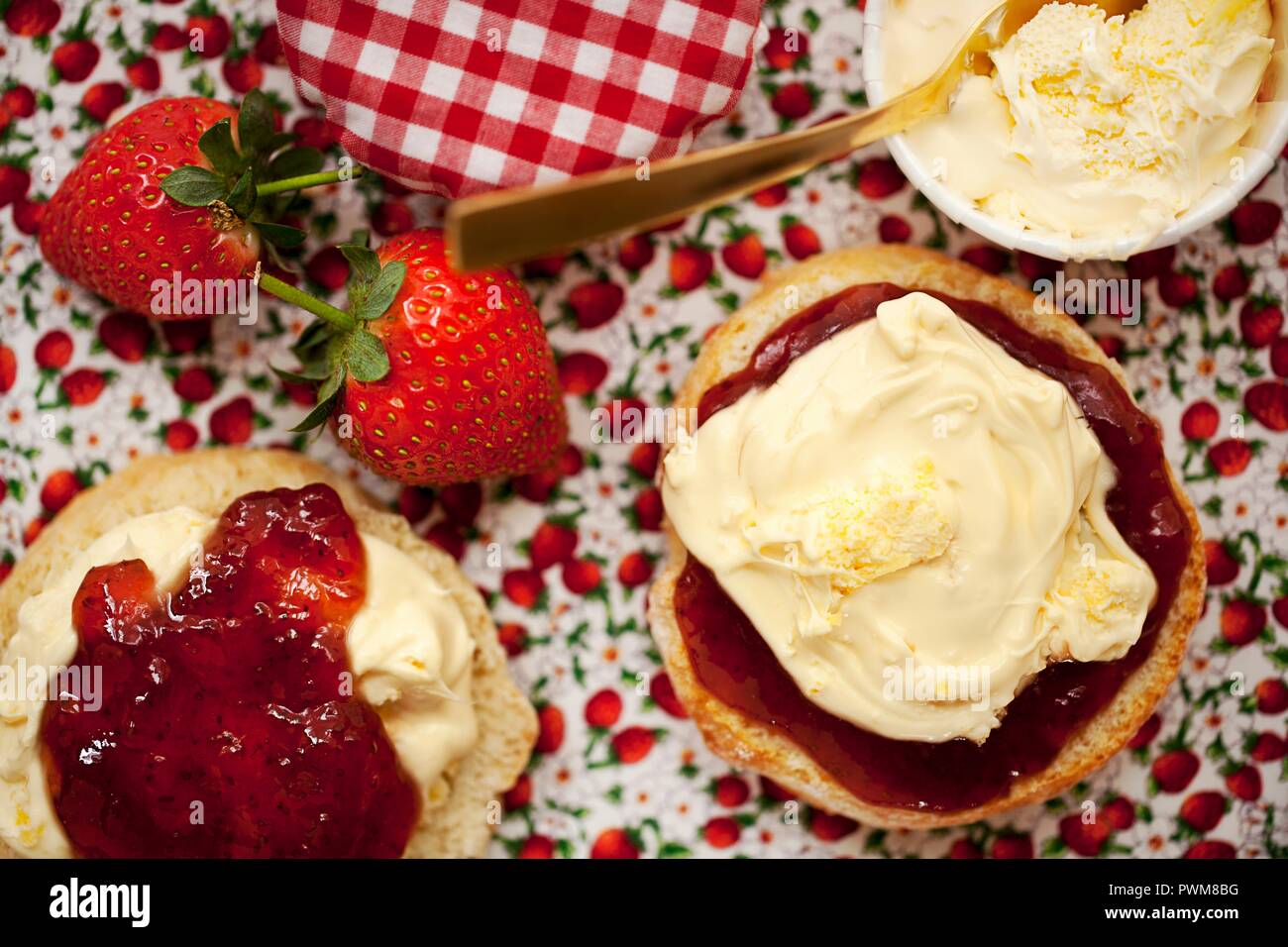 Un cornetto diviso a metà e rabboccato con clotted cream e confettura di fragole Foto Stock