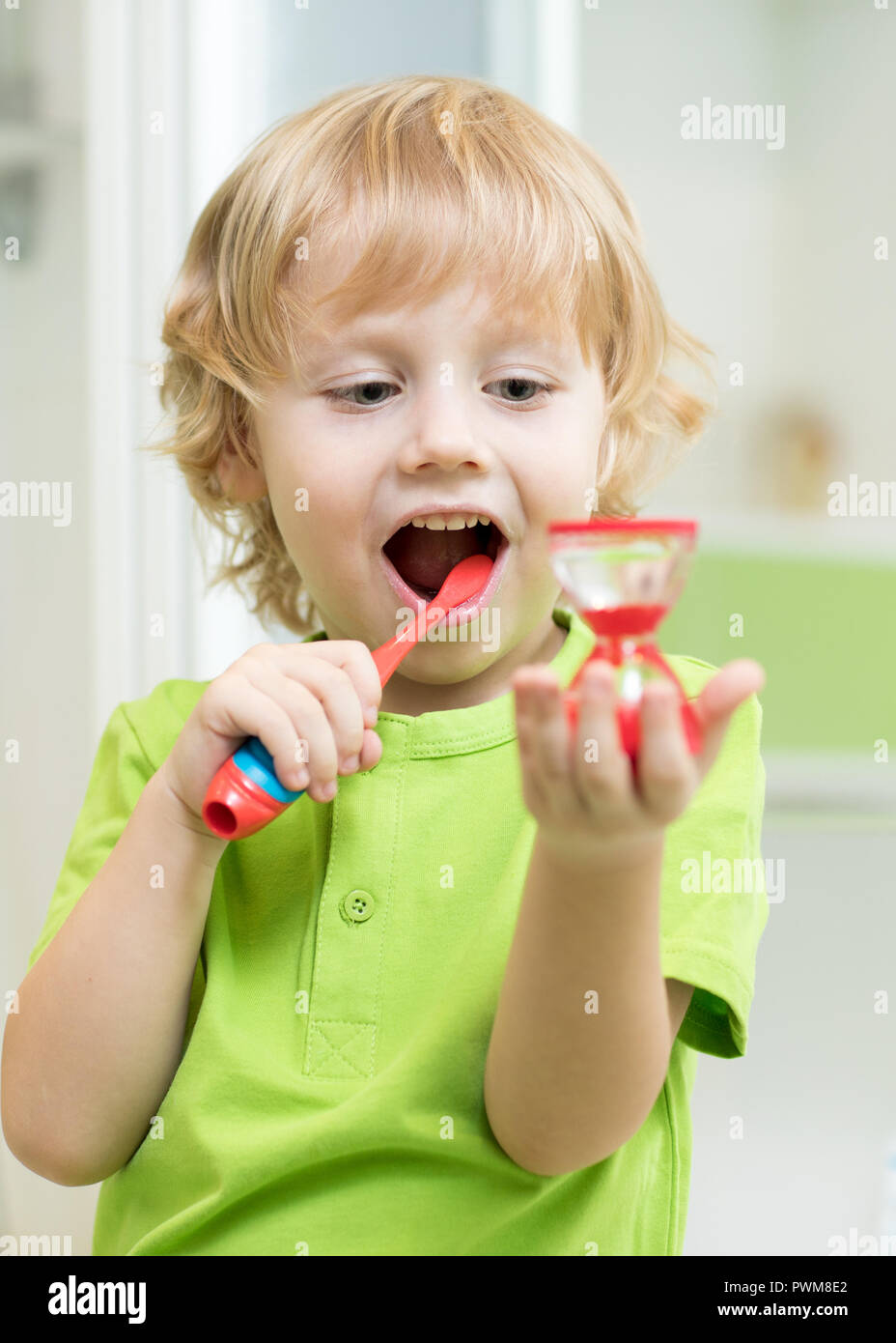 Bambino ragazzo la pulizia i suoi denti e guardando la clessidra Foto stock  - Alamy