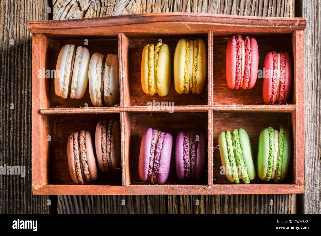 Amaretti colorati in una vecchia scatola di legno Foto Stock