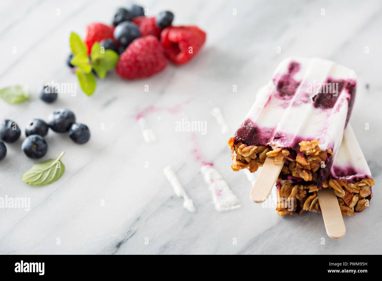 Yogurt, berry e granola popsicles colazione sulla superficie di marmo Foto Stock