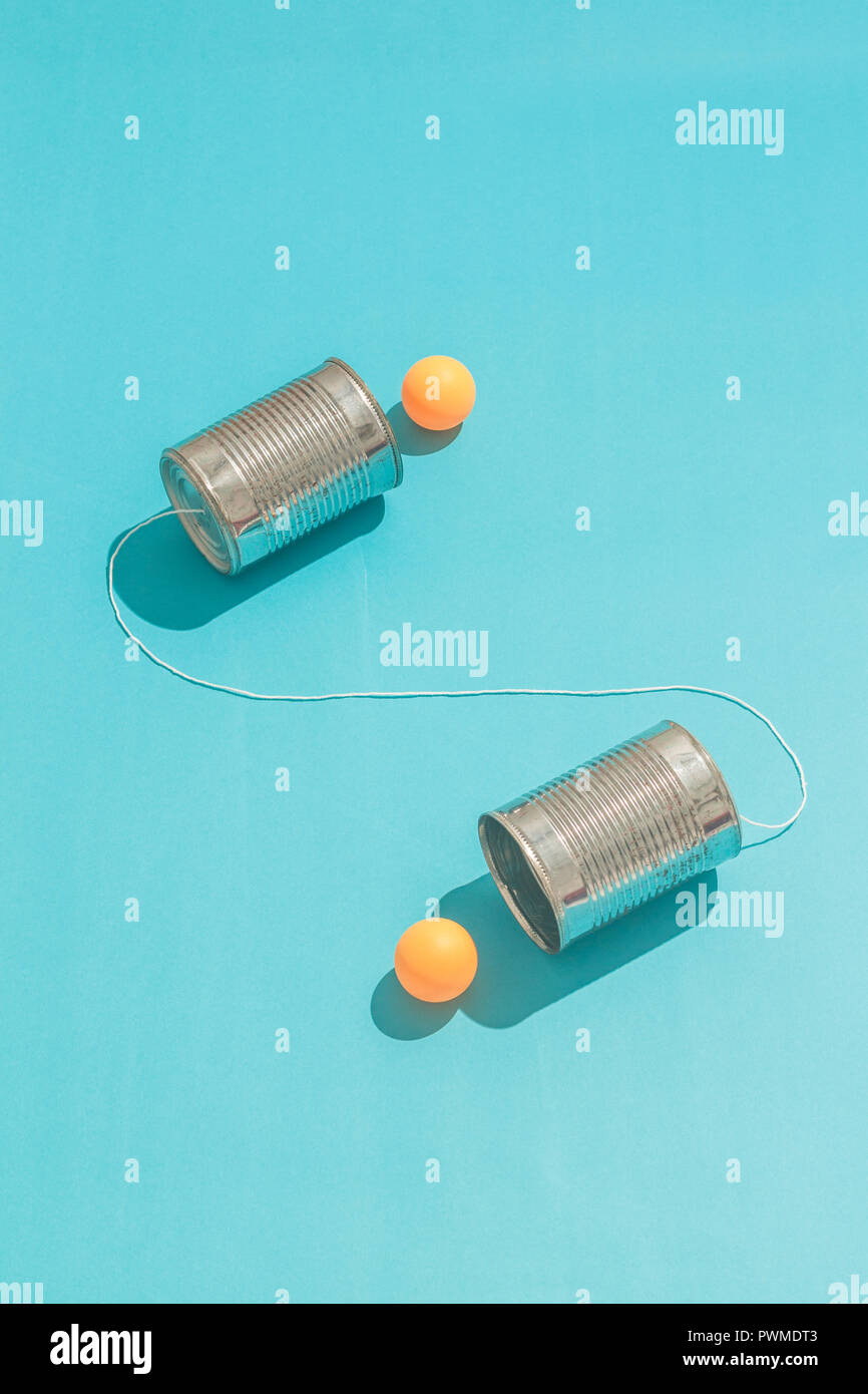 Due orange ping pong palla conversazione attraverso lo stagno può telefono Foto Stock