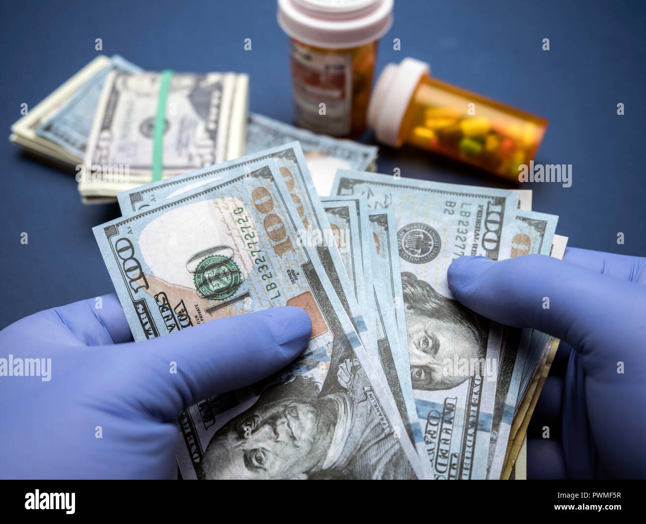 Medico con guanti in lattice blu a contare centinaia di fatture del dollaro in un ospedale Foto Stock