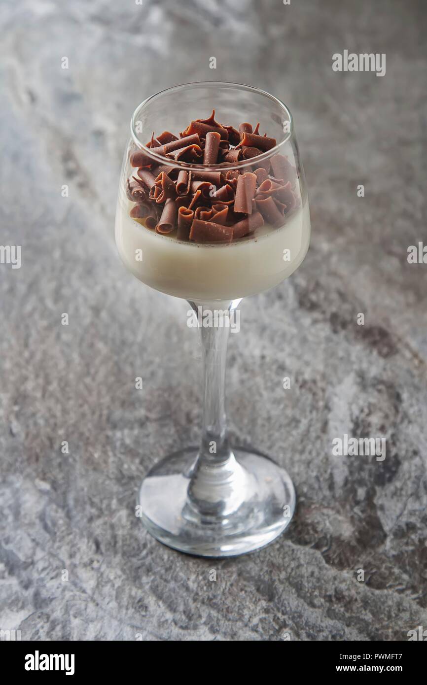 Panna cotta con i riccioli di cioccolato in un bicchiere da dessert Foto Stock