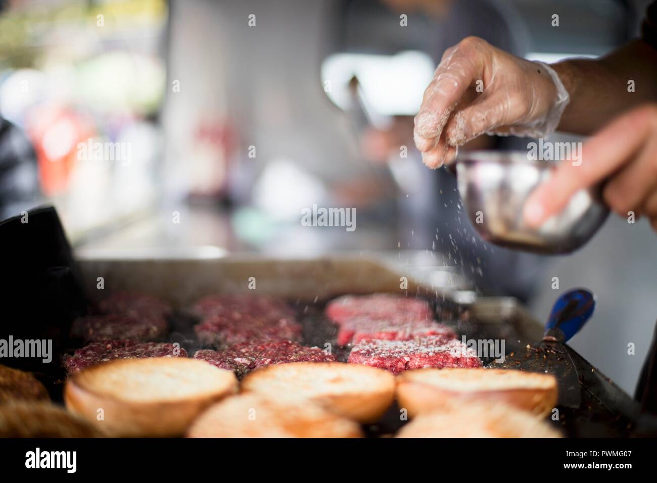 Patties di carne essendo condito con sale Foto Stock