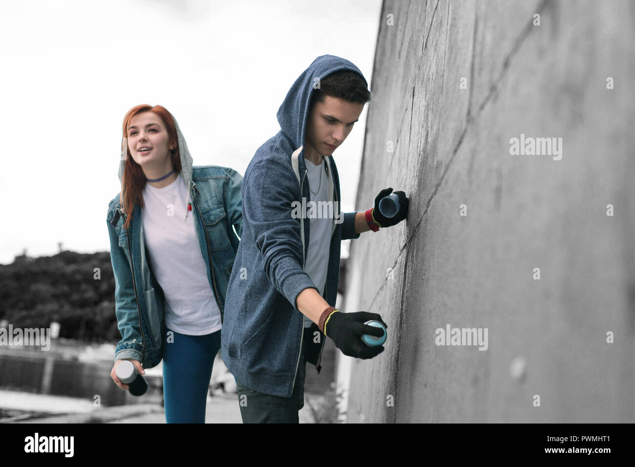 Due adolescenti che indossano giacche con disegno hoodies graffiti in città Foto Stock