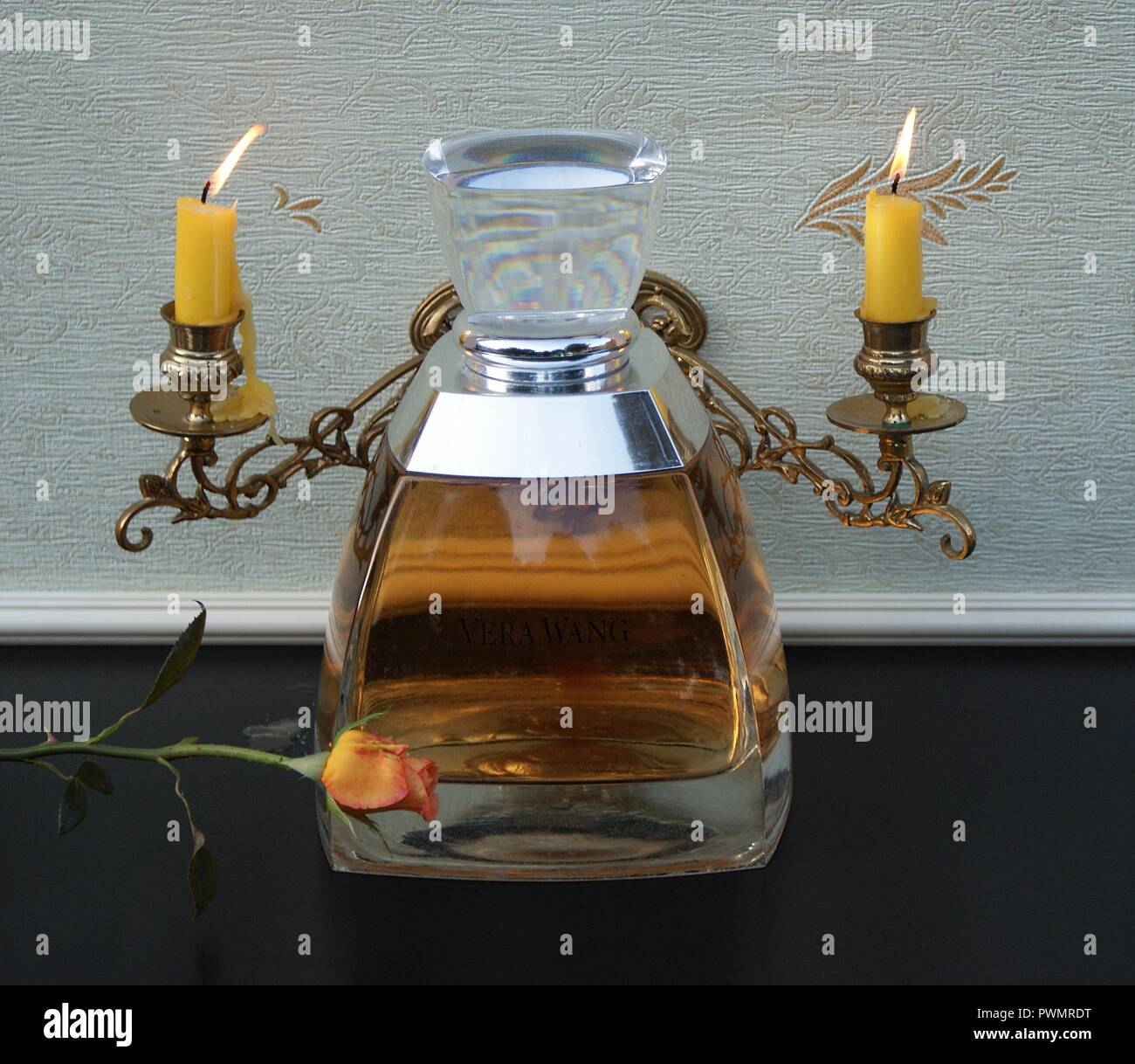 Vera Wang, fragranza per signore, grande bottiglia di profumo nella parte anteriore di un pianoforte candelabri con brillanti Candele decorata con una rosa Inglese Foto Stock