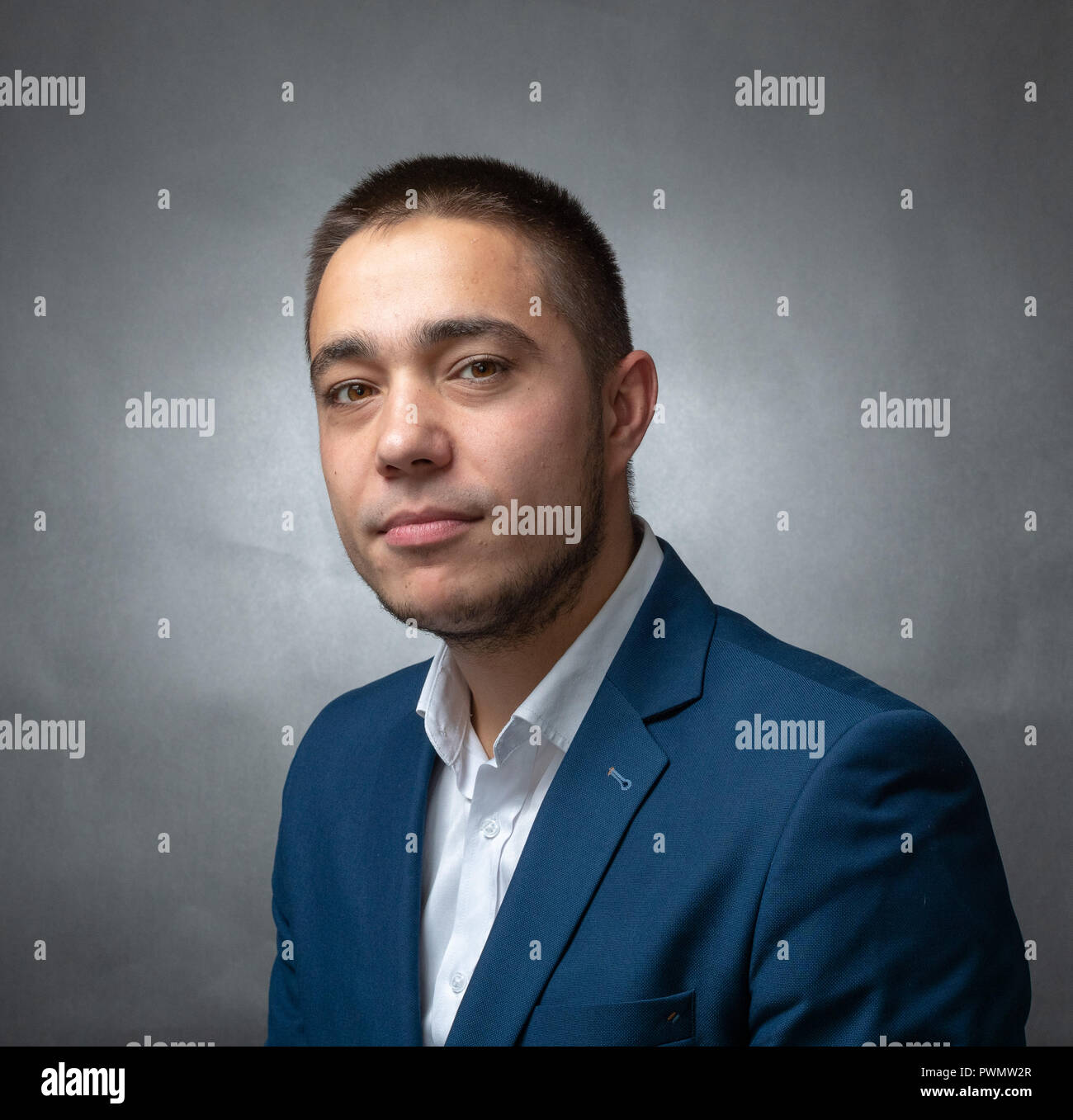 Bel successo imprenditore in tuta blu seduto e mostrando espressioni Foto Stock
