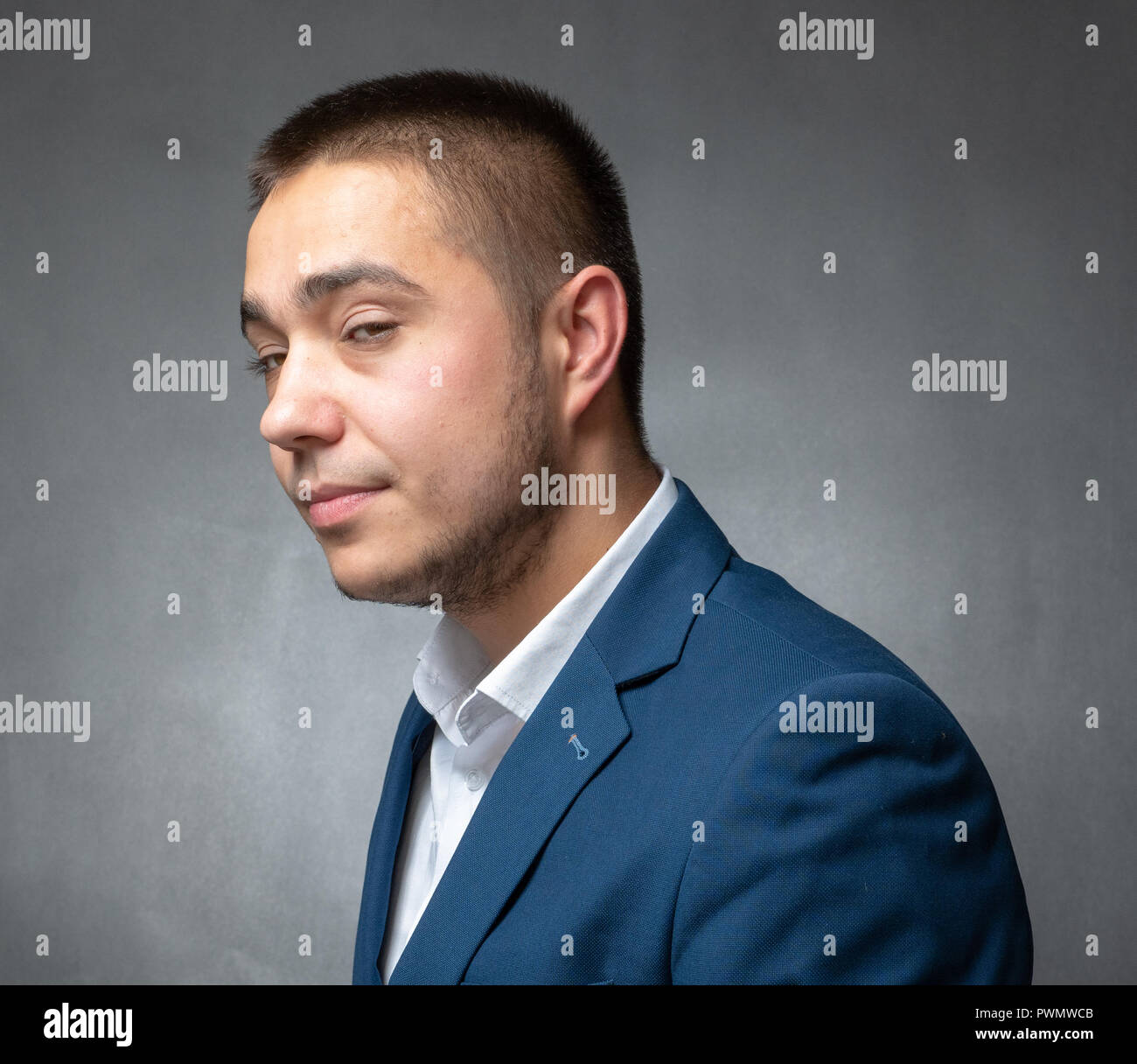 Bel successo imprenditore in tuta blu seduto e mostrando espressioni Foto Stock