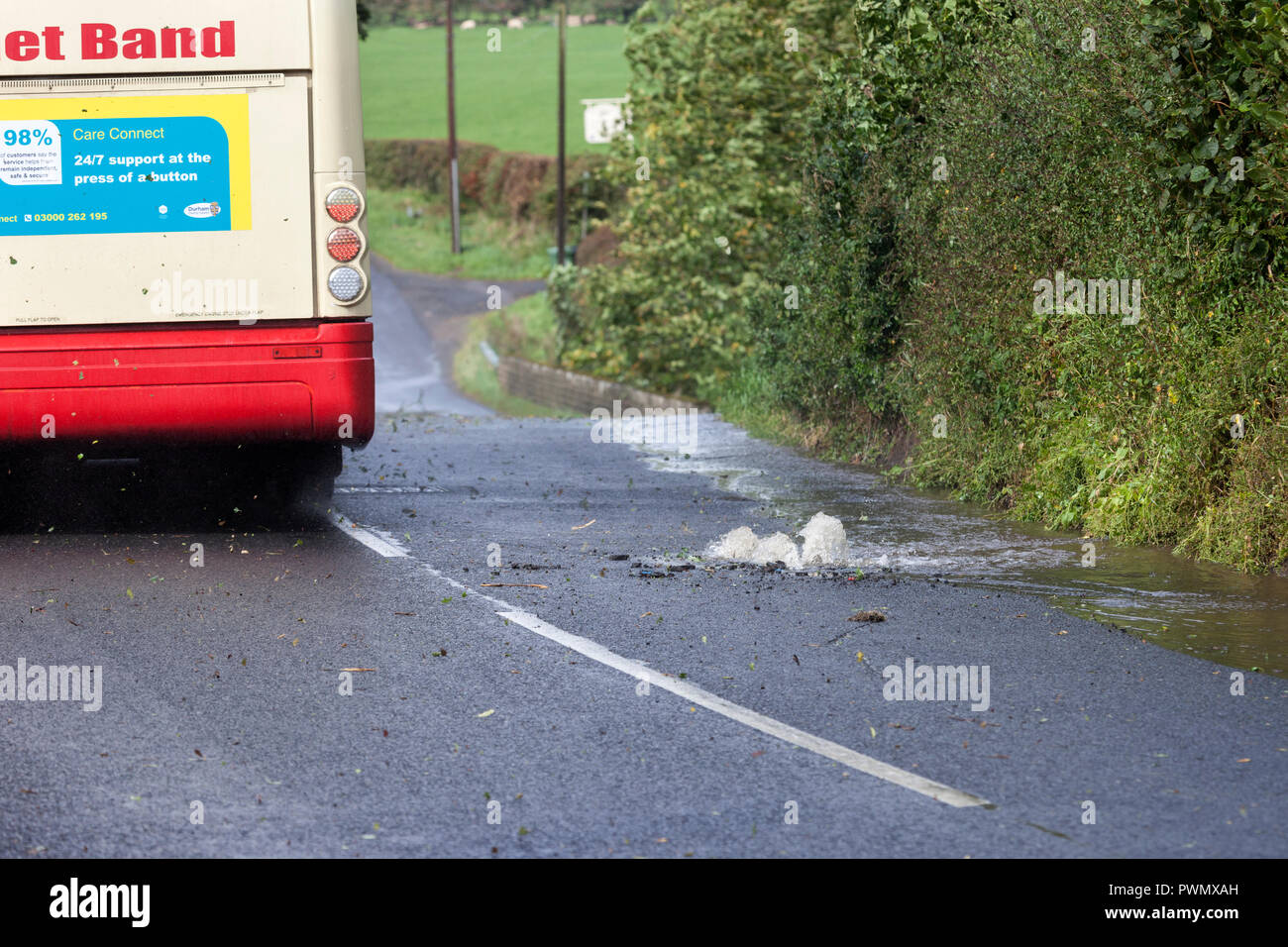 Un Bus azionamento oltre una raffica di acqua nella principale strada, County Durham, Regno Unito Foto Stock