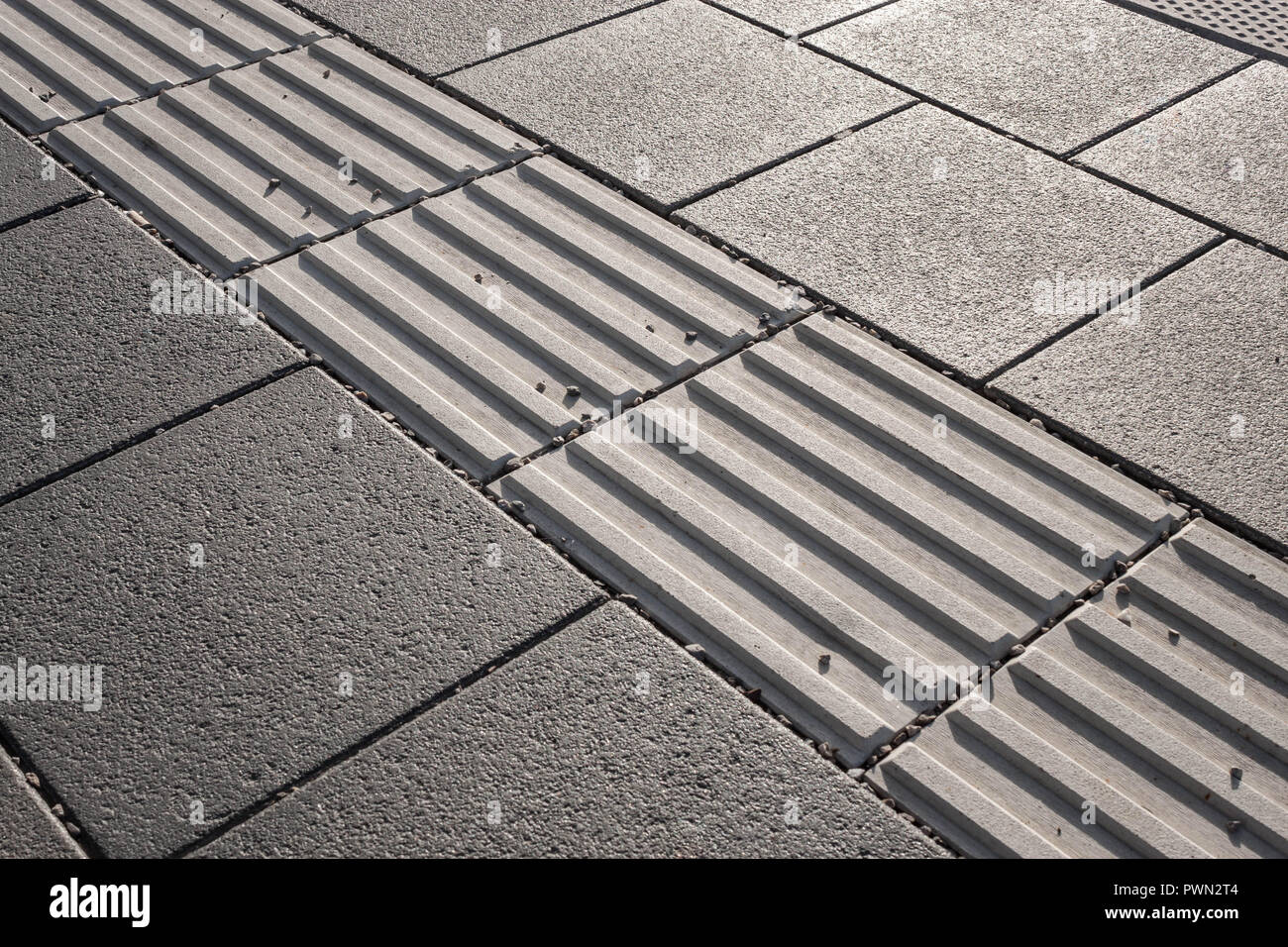 Linea di luci di avvertimento pericolo con pavimentazioni tattili lungo il bordo della piattaforma alla stazione ferroviaria. Pavimentazioni tattili assiste ipovedenti pedoni Foto Stock