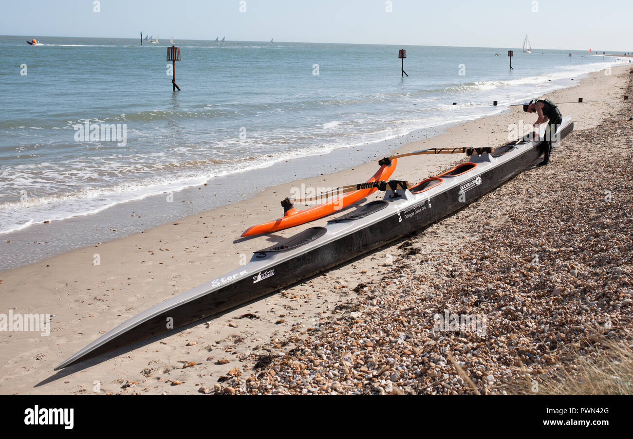 Dragon Boat sulla spiaggia in fase di preparazione da parte di un ragazzo per una gara di team Foto Stock
