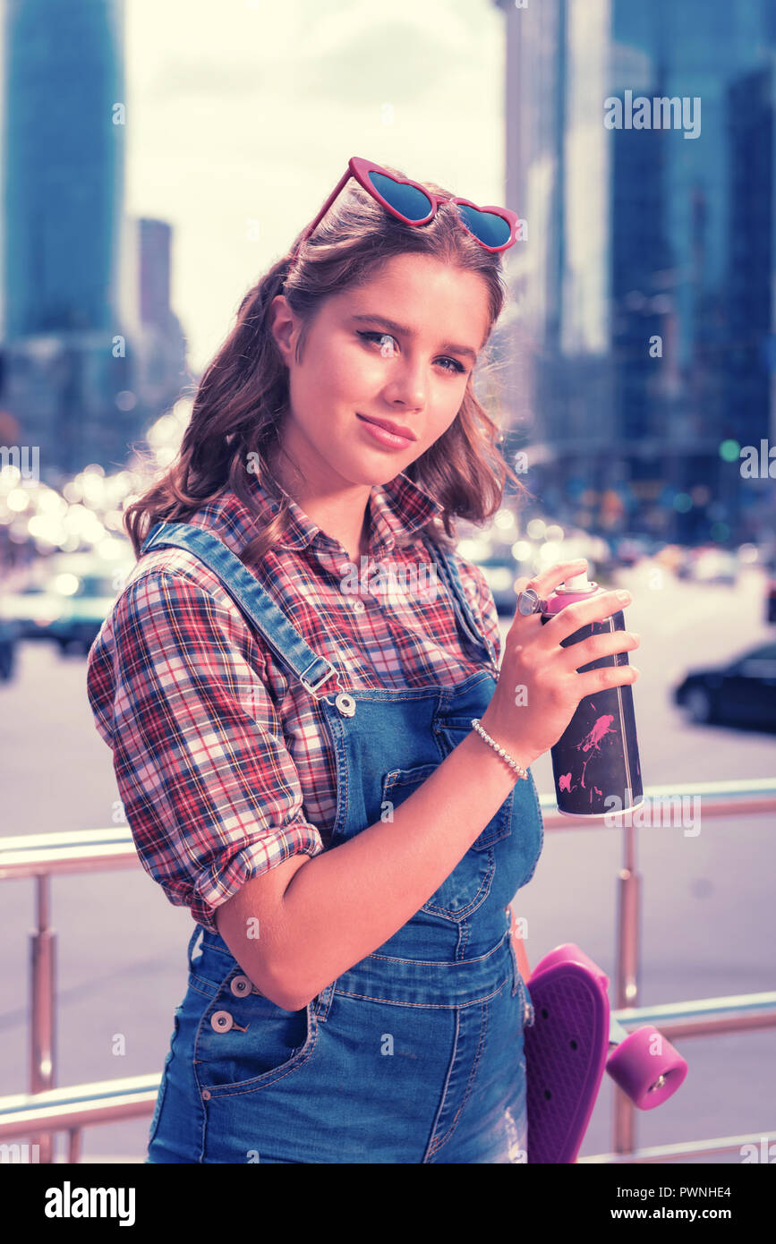 Moderno stile di strada ragazza con energy drink e il suo skateboard viola Foto Stock