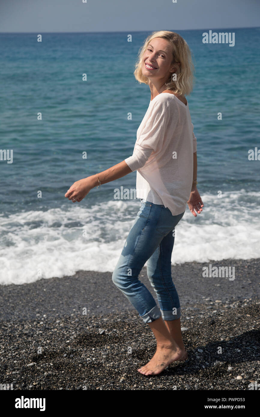 Bella donna sorridente camminando lungo il mare. Foto Stock