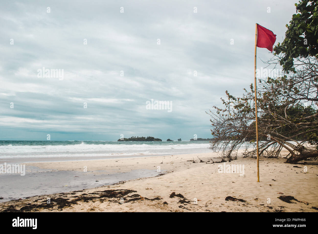 Bandiera rossa sulla ventosa di sabbia bianca di rana rossa Beach, un isola dei Caraibi al largo della costa di Panama Foto Stock
