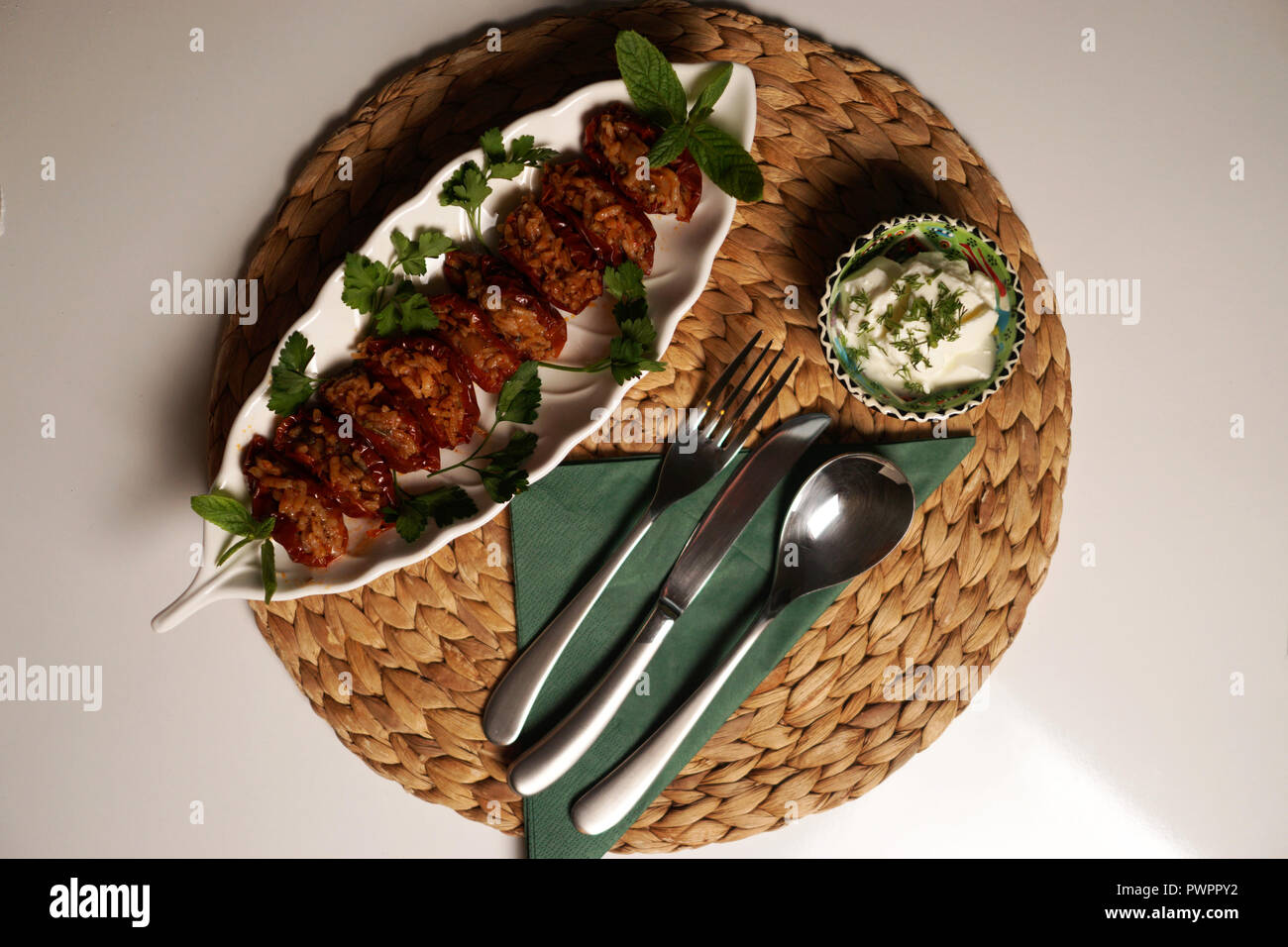Appetitosi Ripieni fatti in casa peperoni rossi serviti con yogurt da cucina turca. Oggetti per il servizio da tavola e yogurt in background. Foto Stock