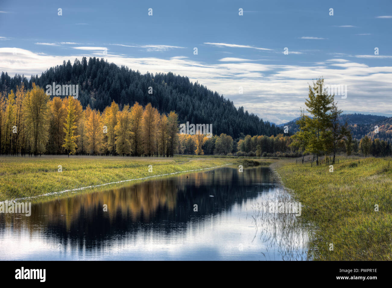 Acqua calma del canale riflette le nuvole nel parzialmente cielo blu su una giornata autunnale vicino Bonners Ferry, Idaho. Foto Stock